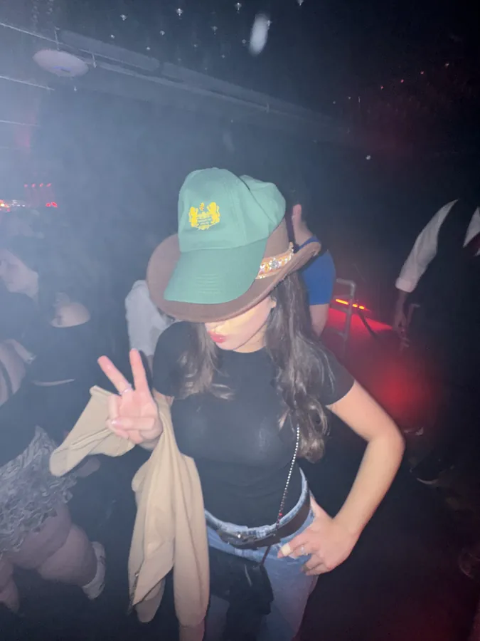 Guest in a Maison of House cap flashing a peace sign